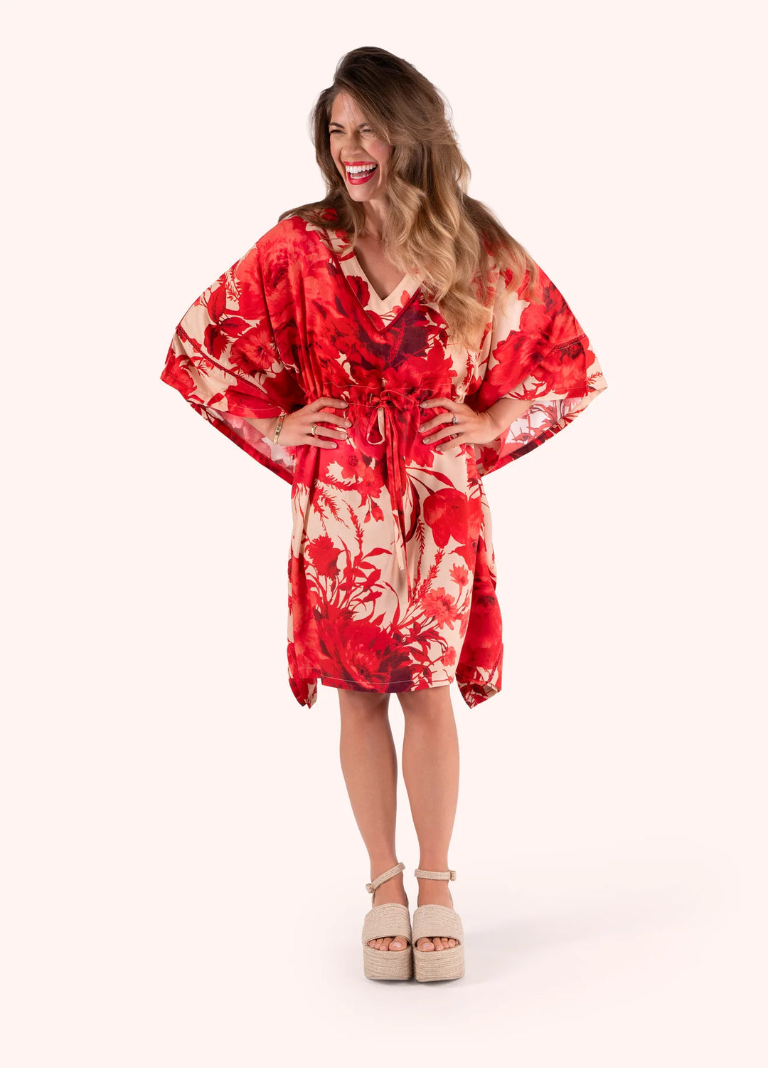 Woman wearing a red and white floral dress on a white background
