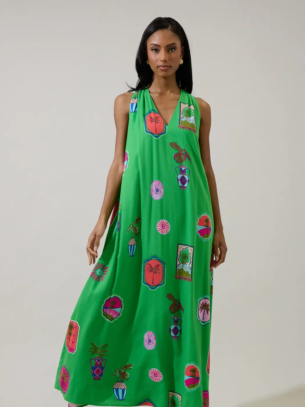 Woman wearing a green dress with colorful floral patterns on a plain background