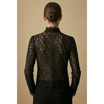 Black lace top worn by a person on a beige background