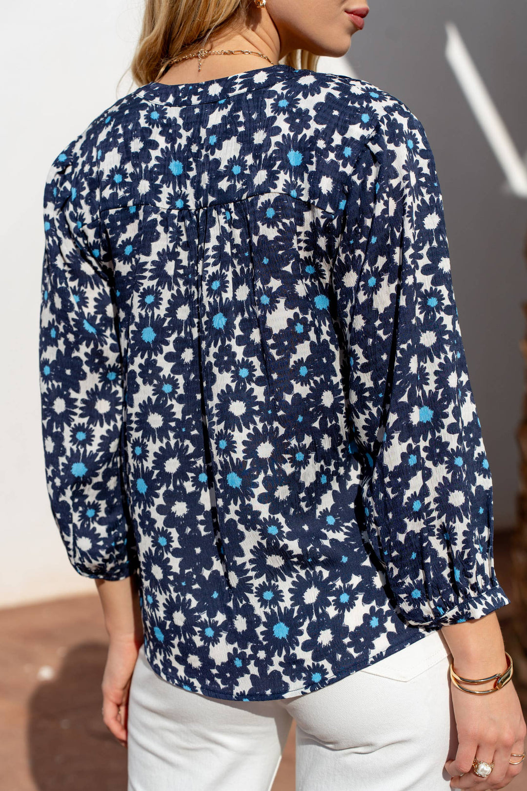 Navy floral patterned blouse worn by a person against a neutral background