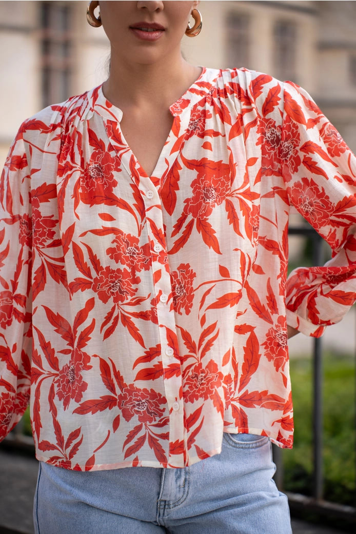 Person wearing a red floral blouse with a blurred background