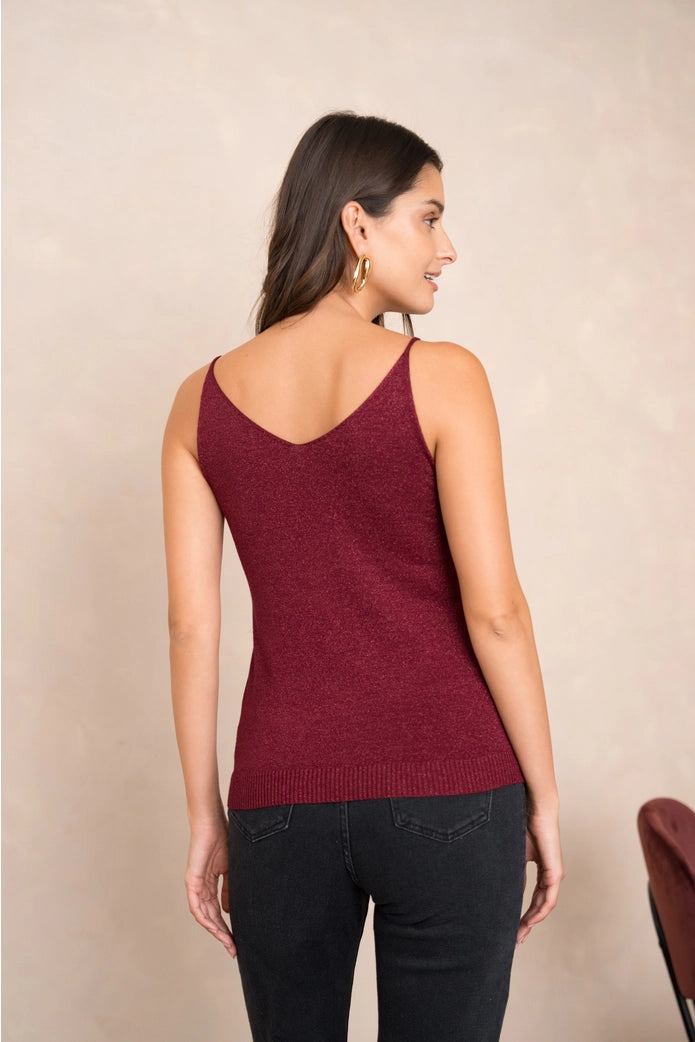 Woman wearing a burgundy tank top against a beige background