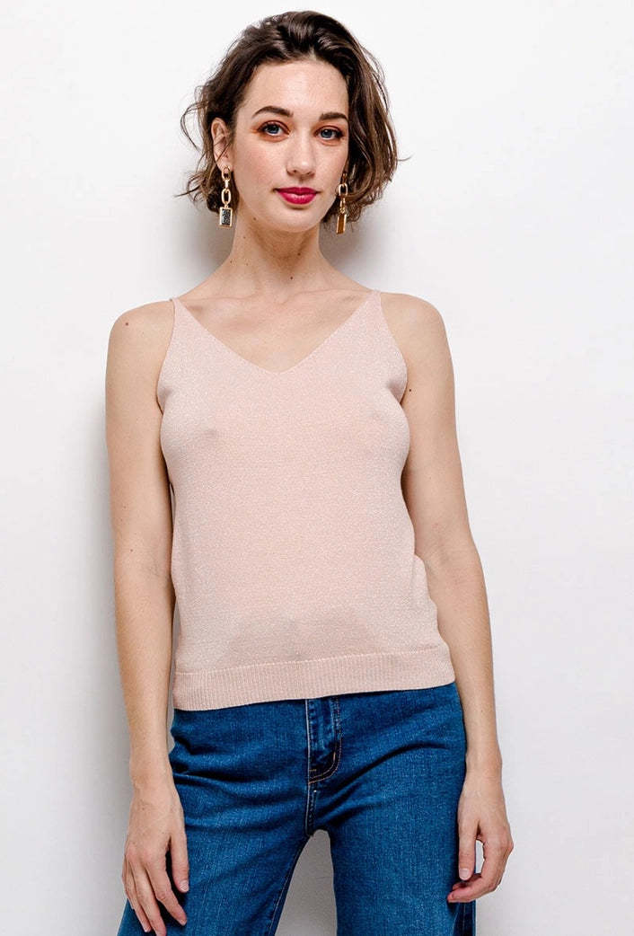 Woman wearing a beige tank top and blue jeans against a white background