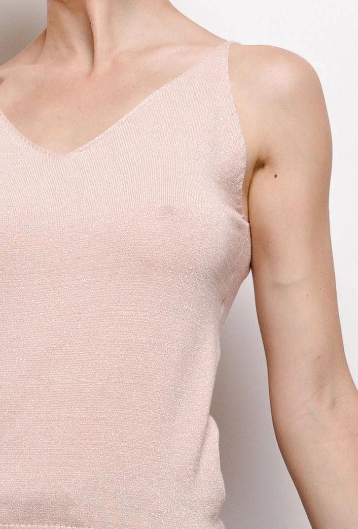 Close-up of a person wearing a light pink sleeveless top against a neutral background