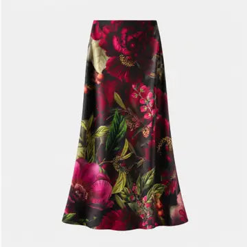 A high-waisted A-line midi skirt featuring a vibrant, dense floral print with red, pink, and green flowers on a black background, shown against a plain light gray studio backdrop.