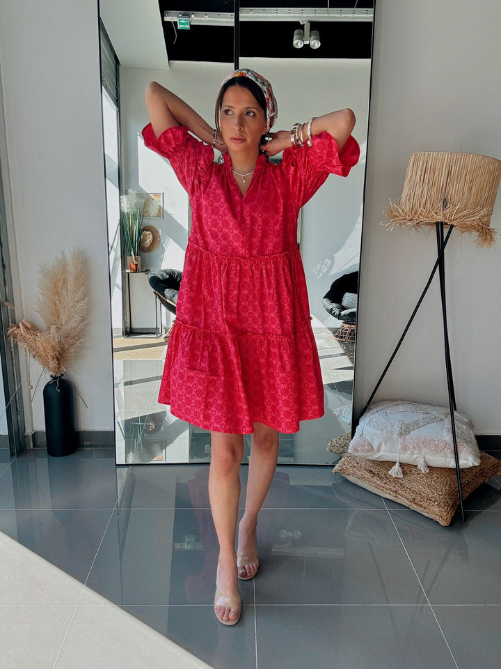 Woman in a red dress standing in front of a mirror in a room with decor elements.