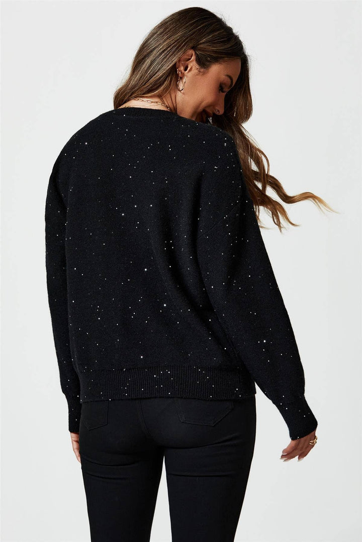 Woman wearing a black sweater with small white dots on a plain background