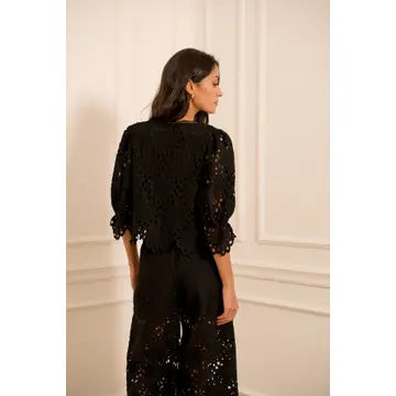 Woman wearing a black lace outfit in a room with white walls.