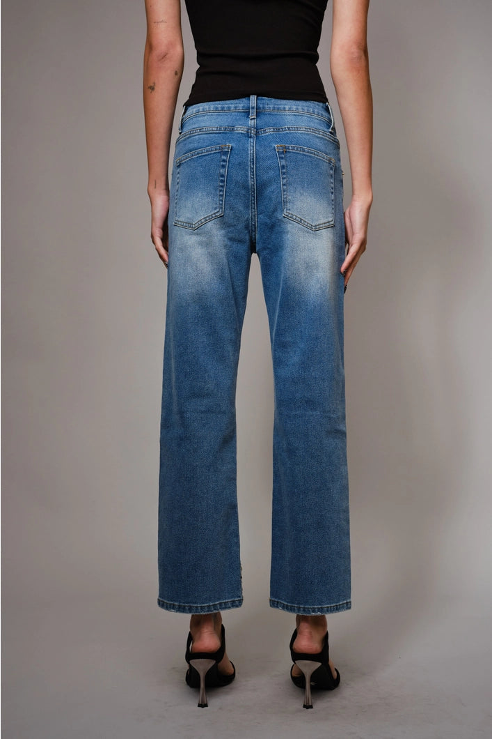 Person wearing blue jeans and a black top on a plain background