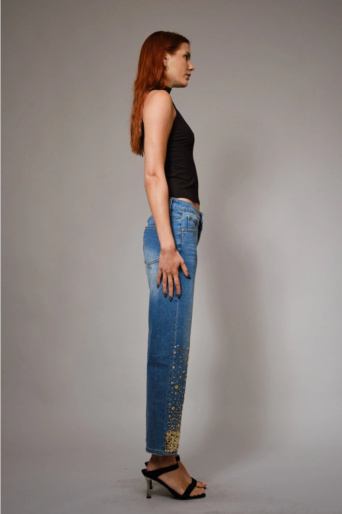 Woman wearing blue jeans and a black top against a gray background