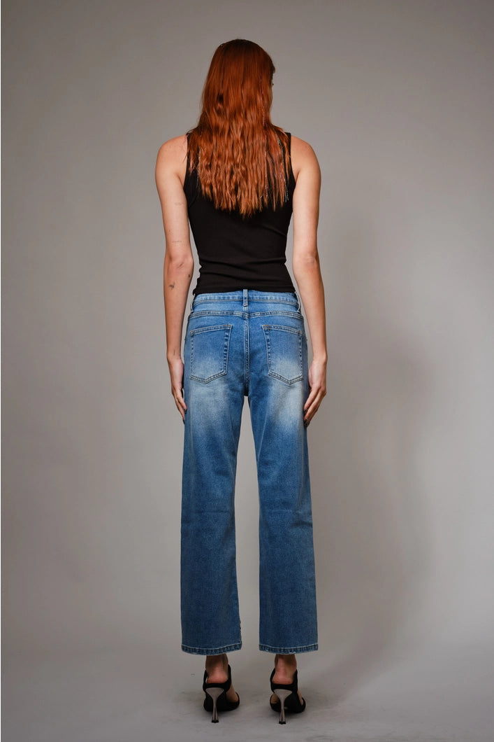 Person wearing blue jeans and a black top on a gray background
