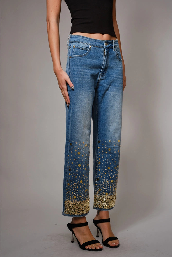Person wearing blue jeans with gold accents on a gray background