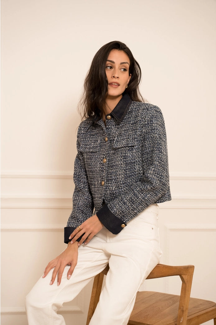 Woman wearing a dark textured jacket with a white background