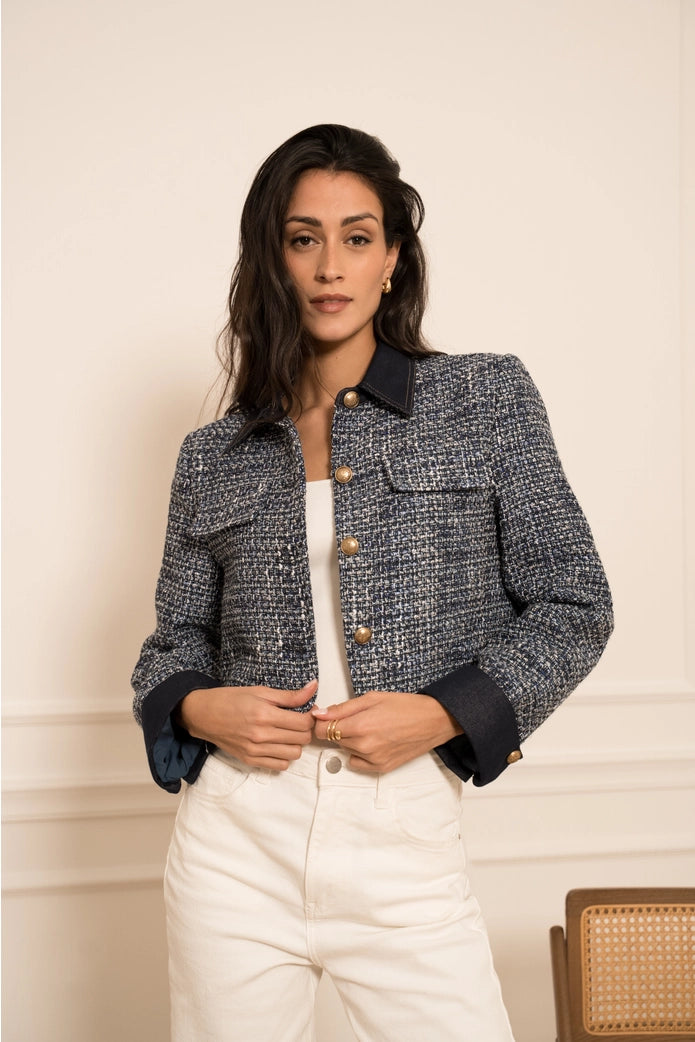 Woman wearing a tweed jacket over a white shirt with a neutral background