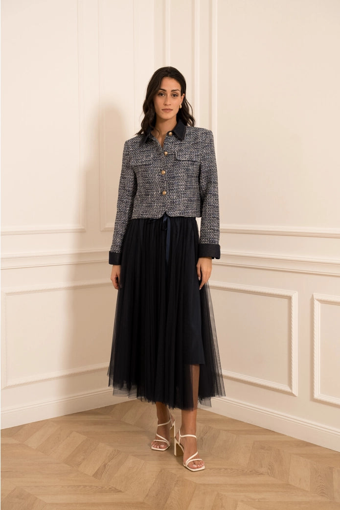 Woman wearing a tweed jacket and black skirt in an elegant room.