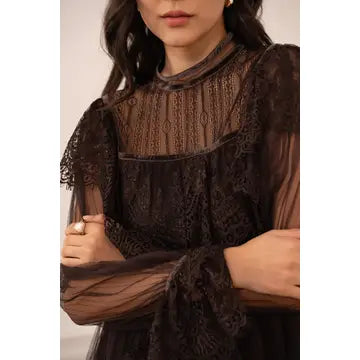 A close-up of a model wearing a black sheer lace blouse with a high mock neck and long flutter sleeves, set against a plain light background.