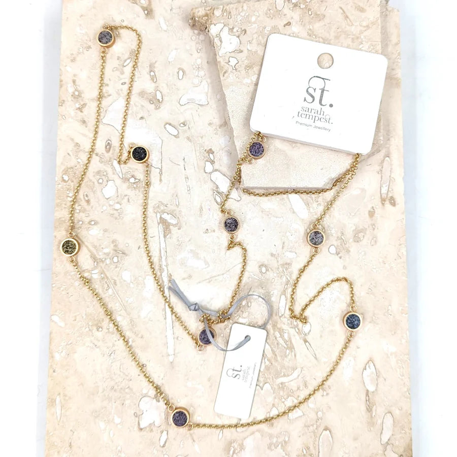 Gold necklace with black accents on a branded card