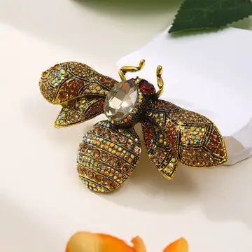 Decorative bee brooch with gemstones on a white surface