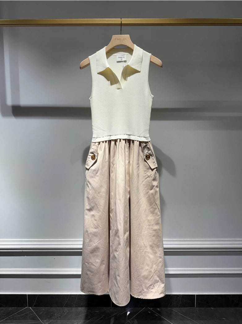 White sleeveless top and beige wide-leg pants on a hanger against a gray wall.