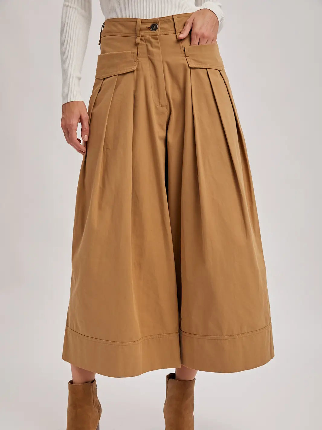 Brown pleated skirt worn by a person on a white background