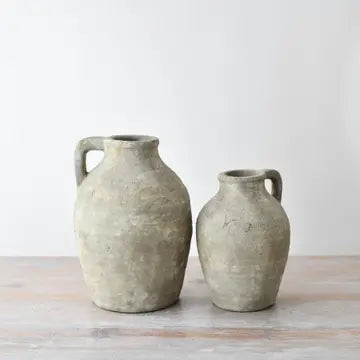 Two rustic clay vases on a wooden surface with a light background