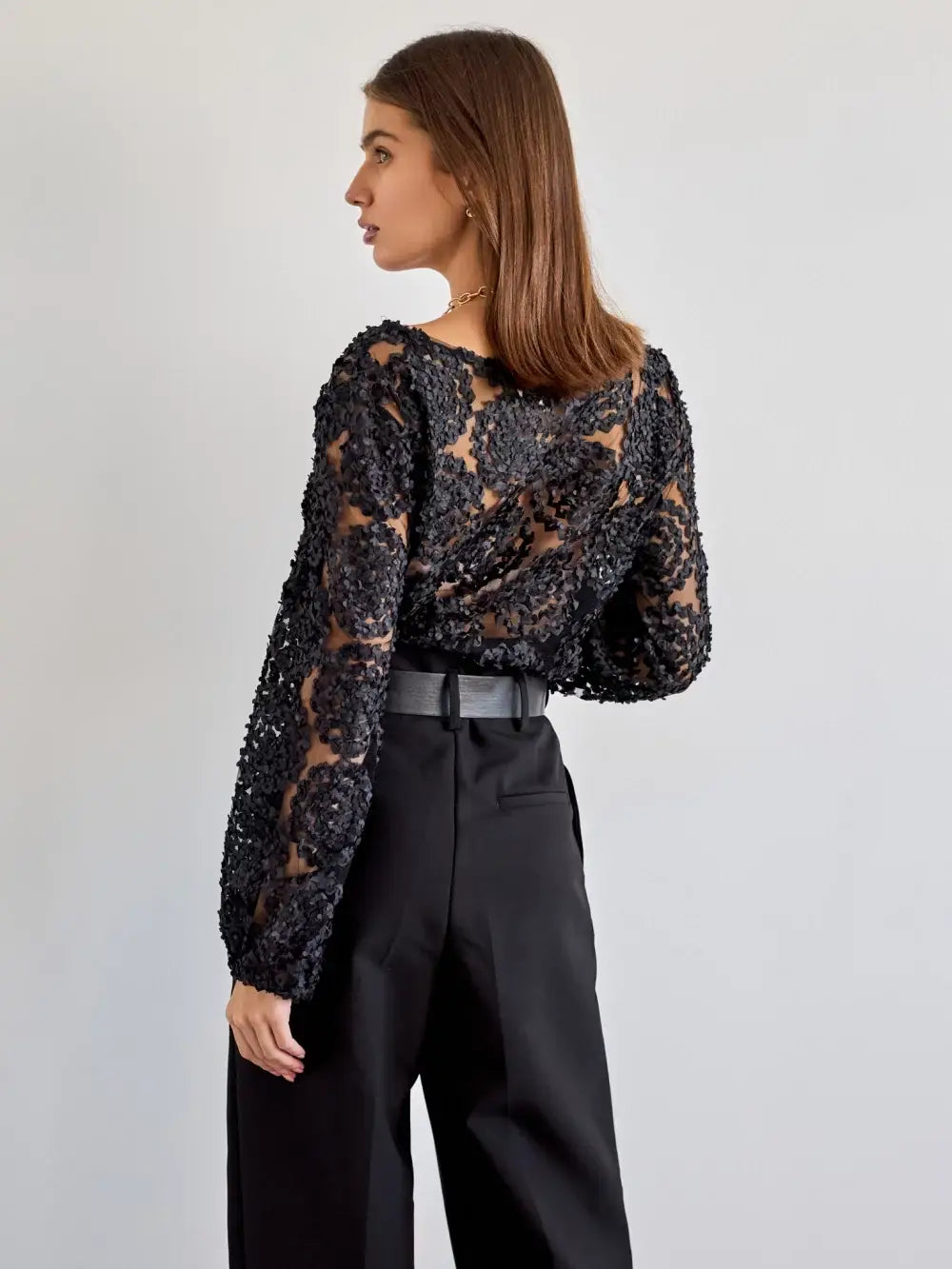 Woman wearing a black sequin top and black pants on a light gray background