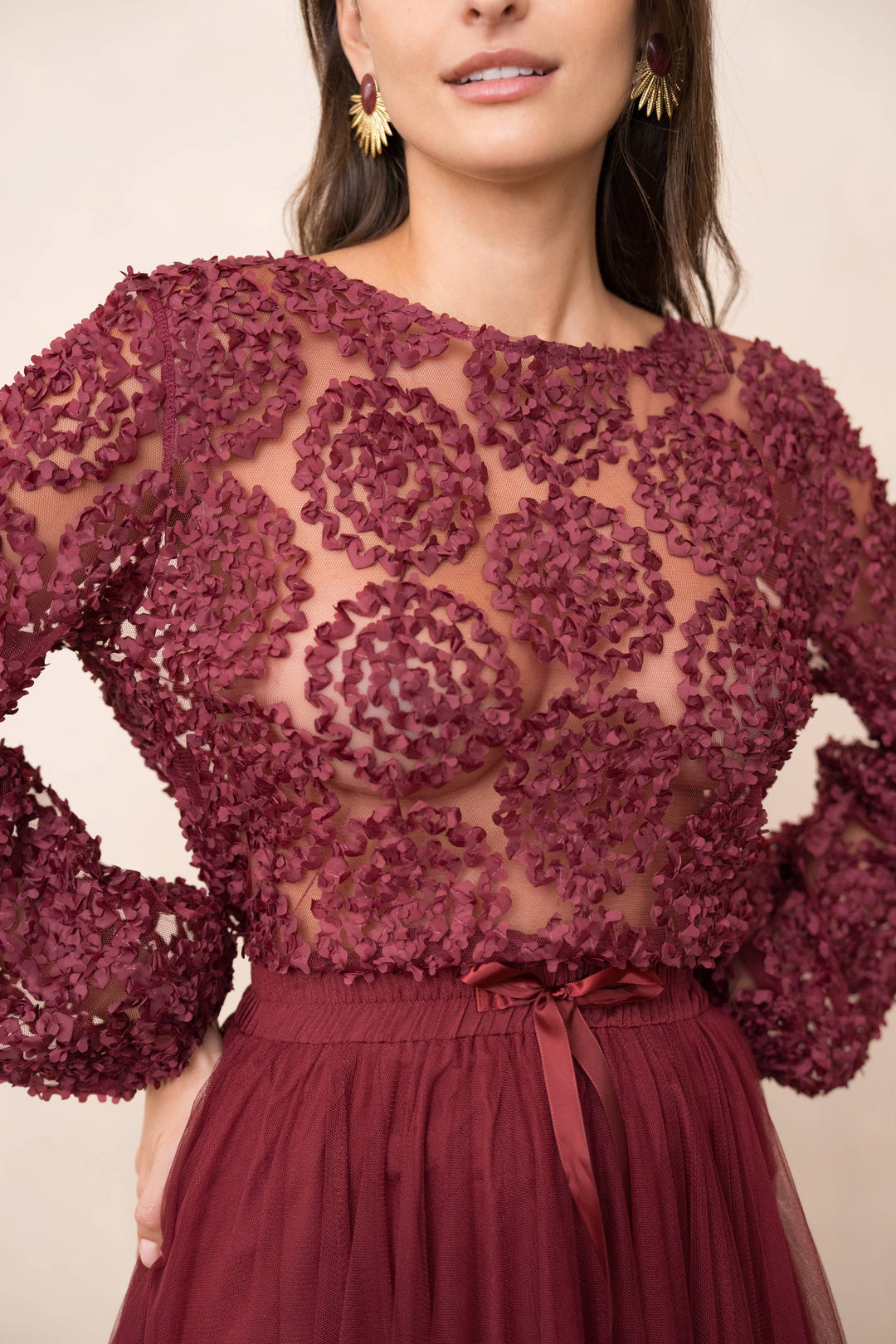 Maroon lace top with long sleeves and a matching skirt on a neutral background