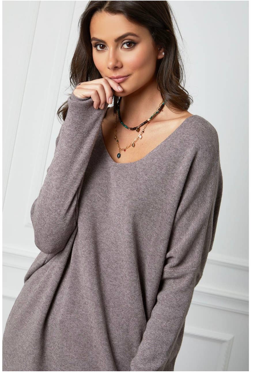 Woman wearing a long-sleeve gray dress against a white background