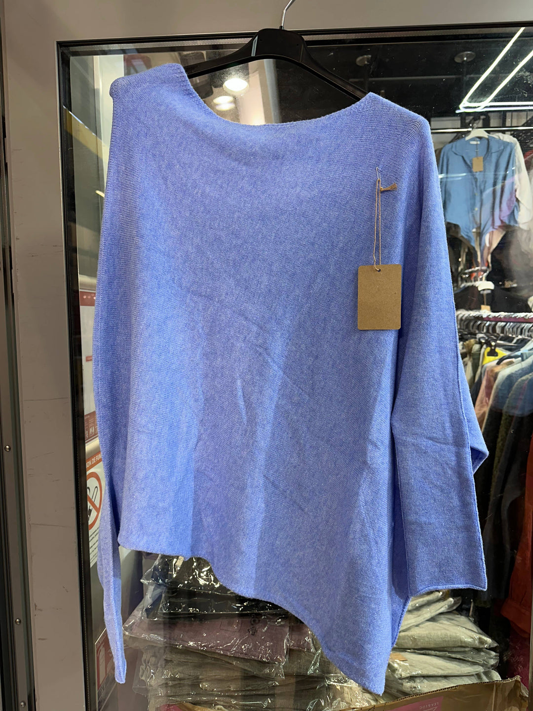 Blue sweater on a hanger with a tag in a store setting