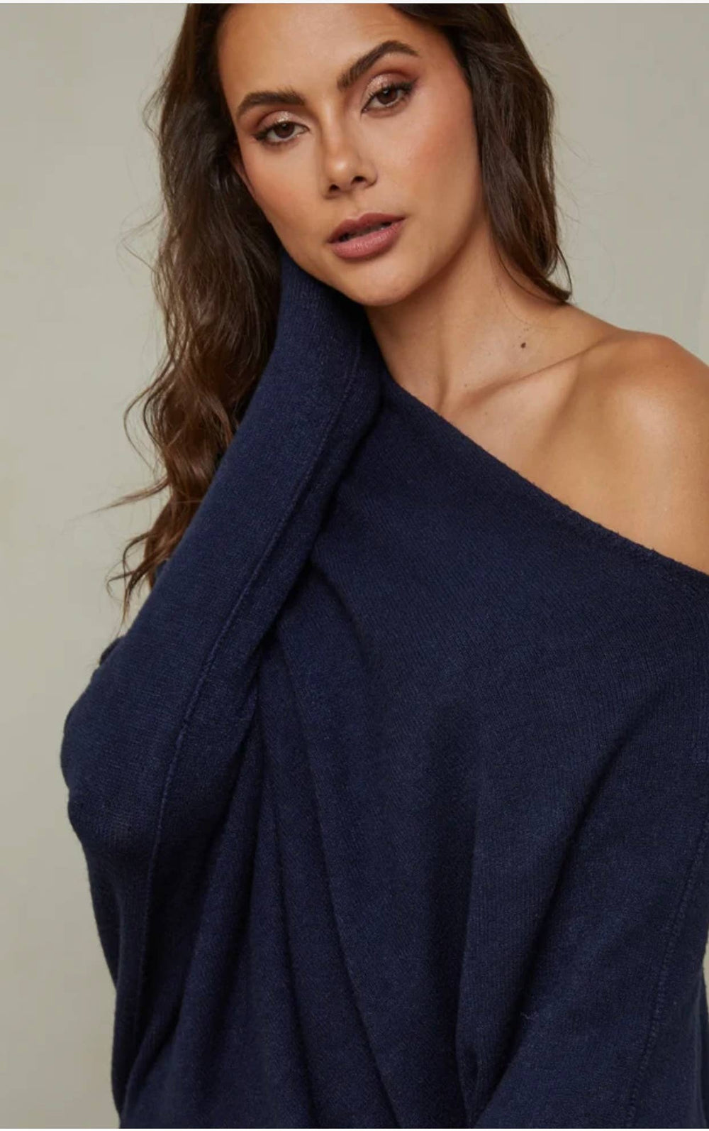Woman wearing a navy blue off-shoulder top against a neutral background