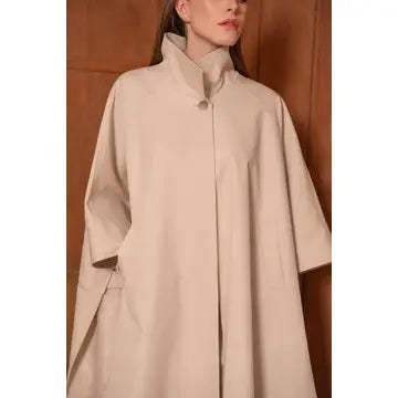 Beige coat worn by a person against a neutral background