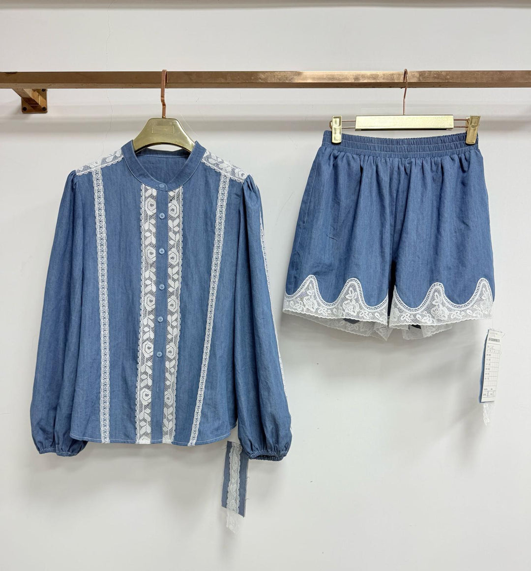 Blue embroidered shirt and shorts set on hangers against a white background