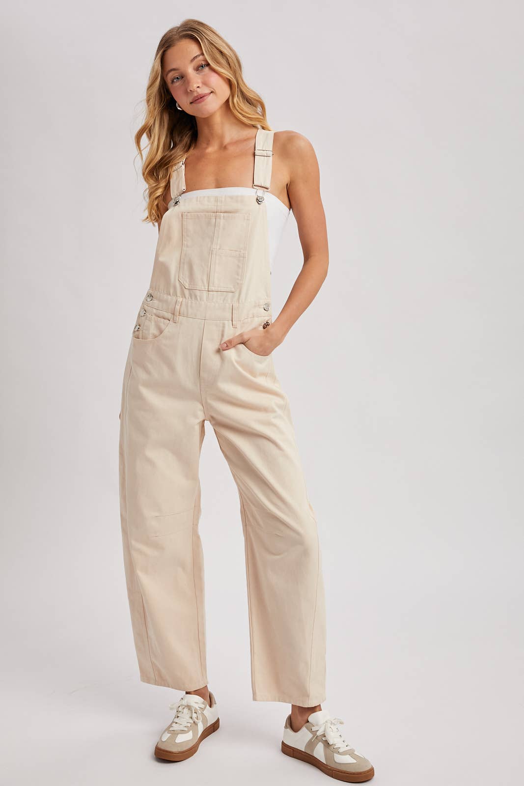 Woman wearing beige overalls on a plain background