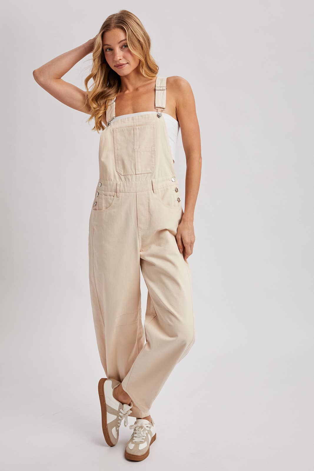Woman wearing beige overalls on a white background