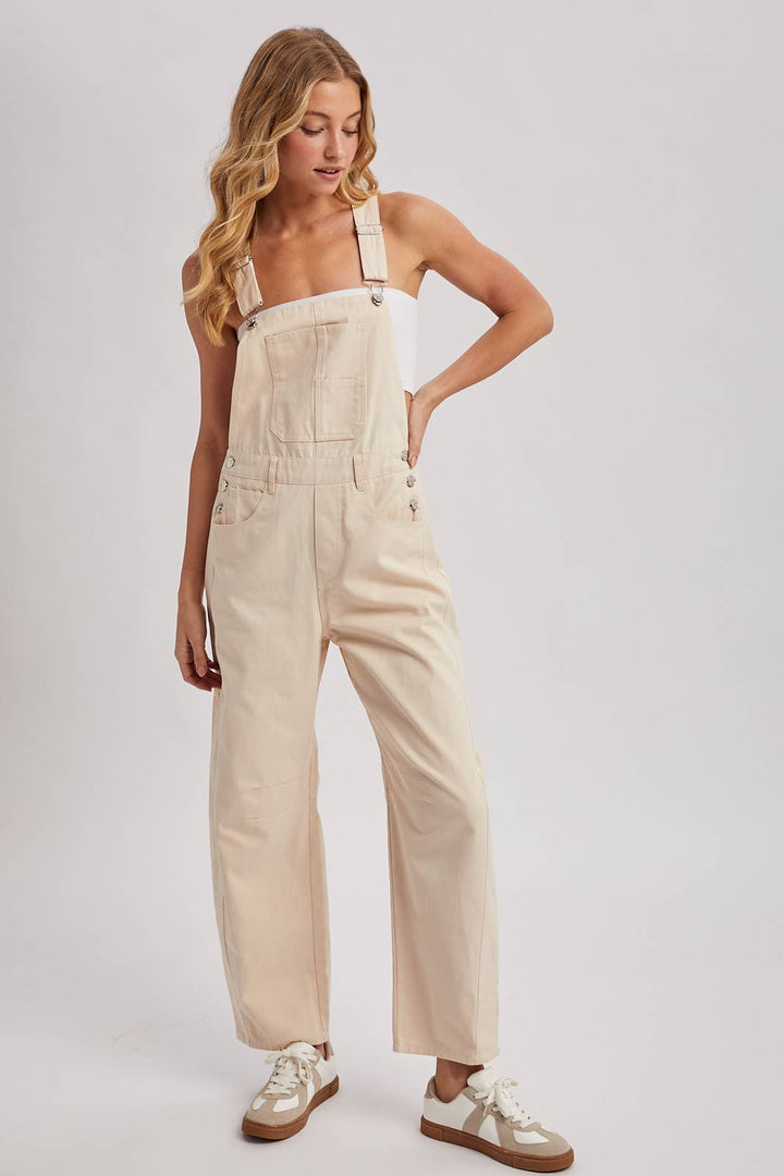 Woman wearing beige overalls on a plain background