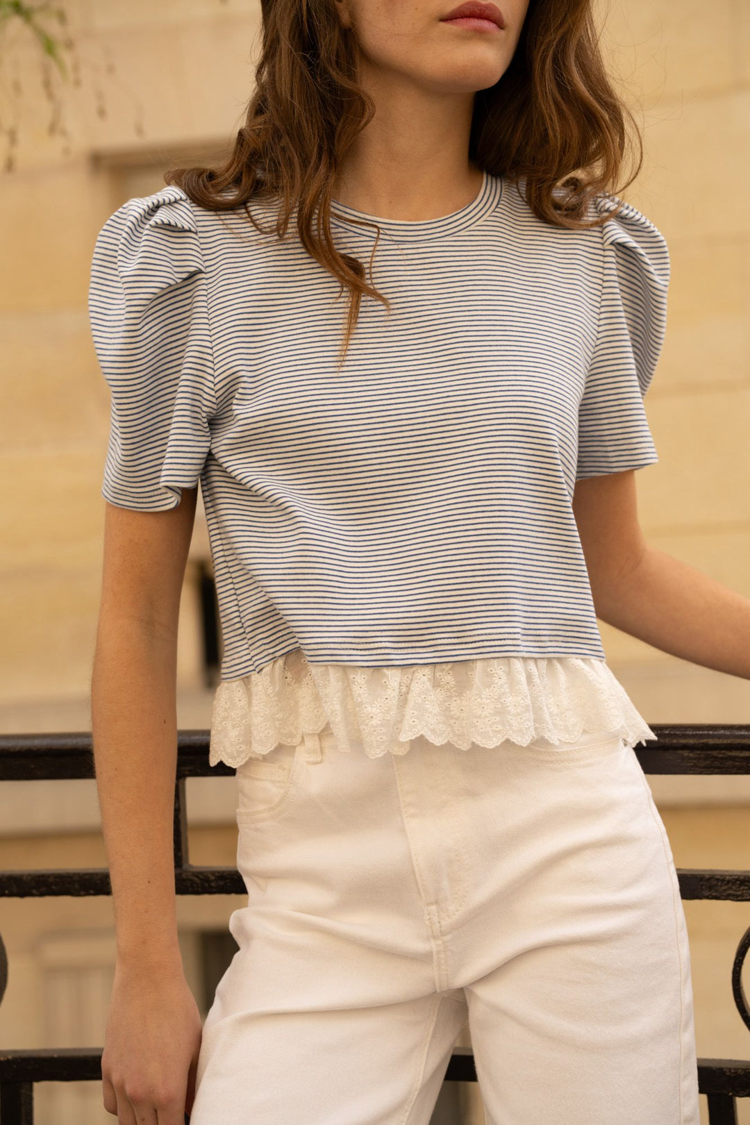 Woman wearing a striped top and white pants with a blurred background
