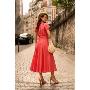 Woman in a red dress walking on a street in an urban setting