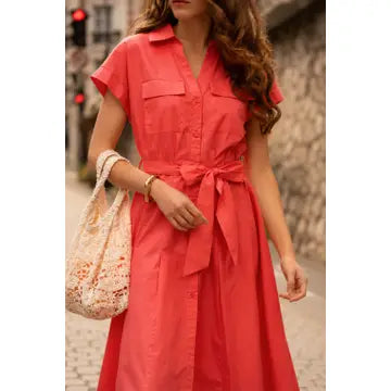 Woman wearing a red dress with a stone wall and traffic light in the background