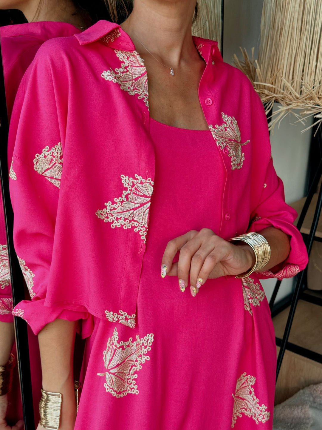 Person wearing a bright pink outfit with gold embroidery in an indoor setting.