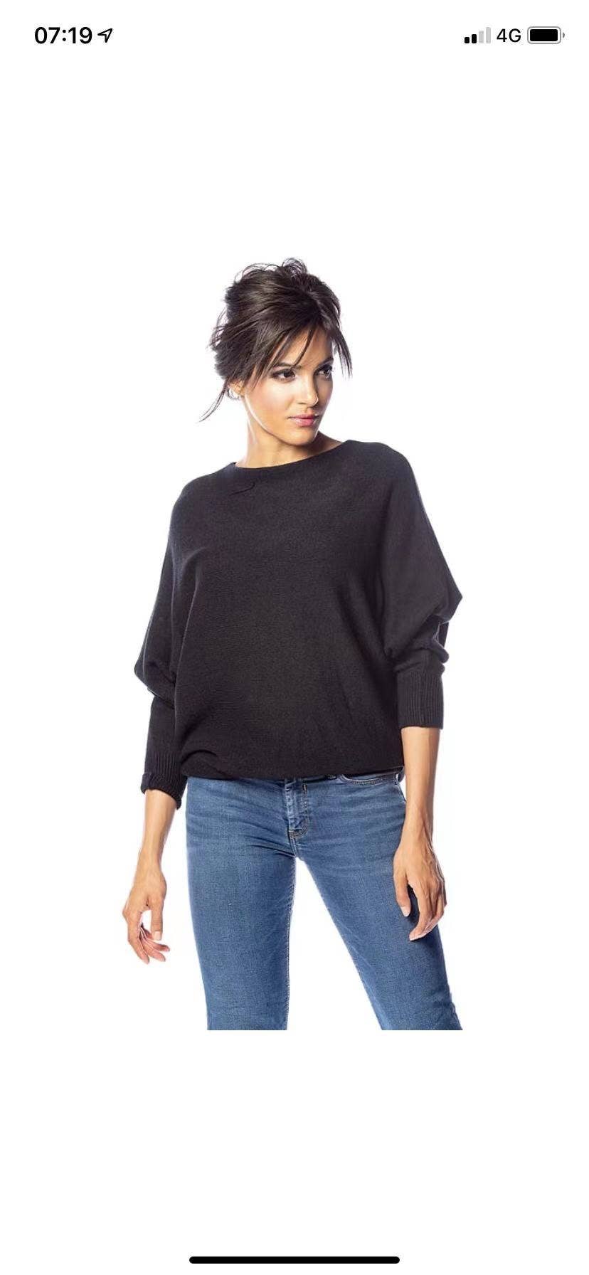 Woman wearing a black sweater and blue jeans on a white background