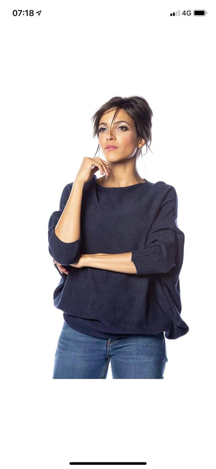 Woman wearing a navy blue sweater and jeans on a white background