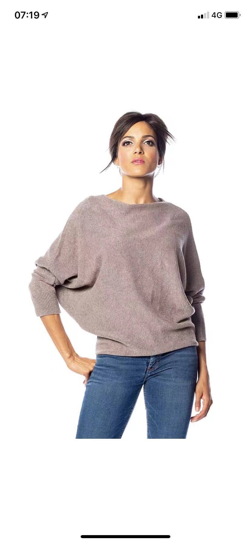 Woman wearing a gray sweater and blue jeans on a white background