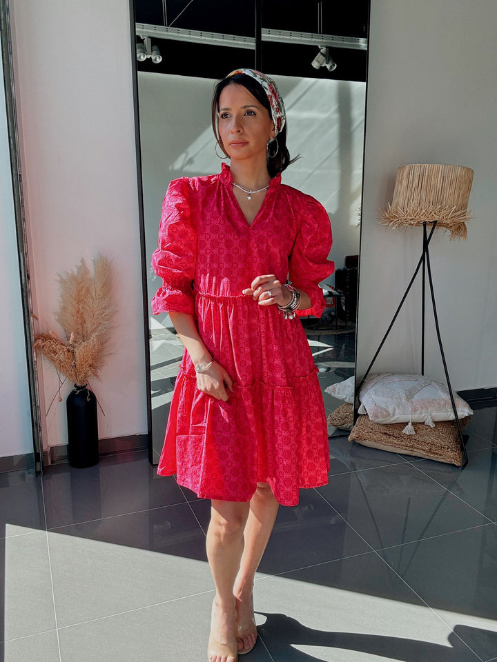 Woman in a red dress standing in a room with a mirror and decor.
