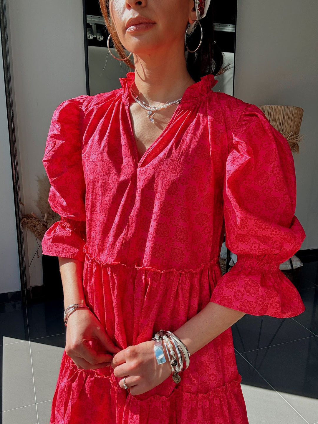 Person wearing a red dress with puffed sleeves in an indoor setting