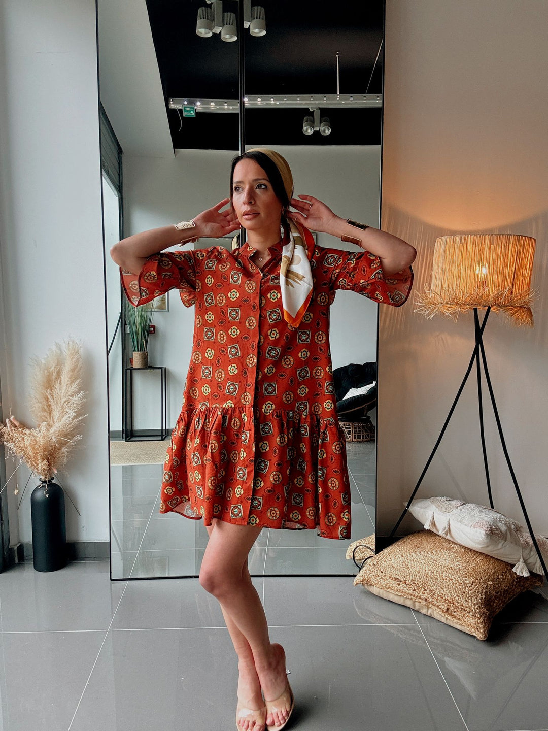 Woman in a red patterned dress standing in a modern interior setting.