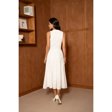Woman in a white dress standing in a room with wooden walls.