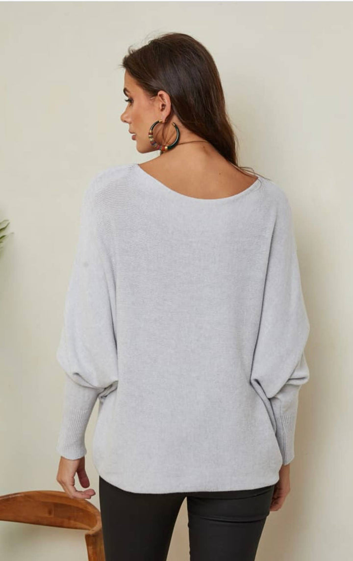 Woman wearing a light gray sweater against a plain background