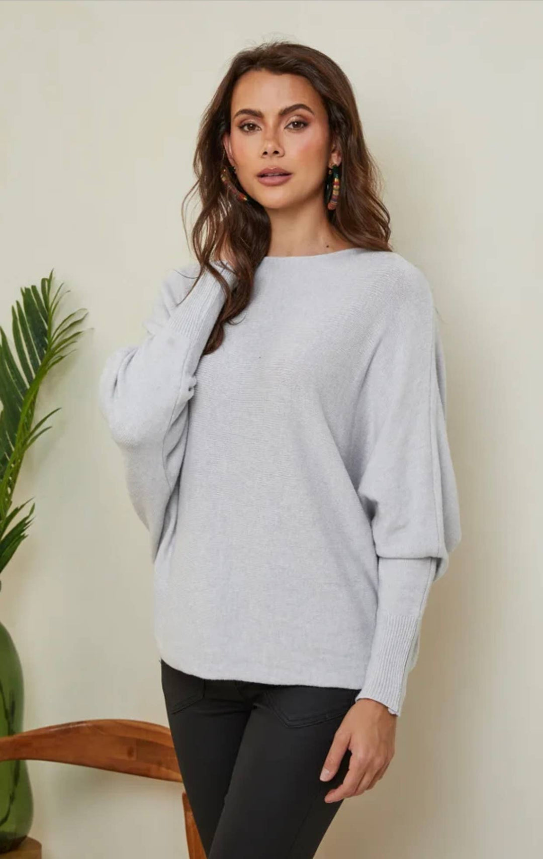 Woman wearing a light gray sweater against a plain background