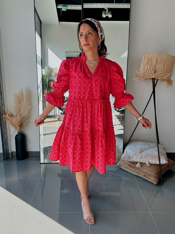 Woman wearing a red dress standing in a modern interior setting.
