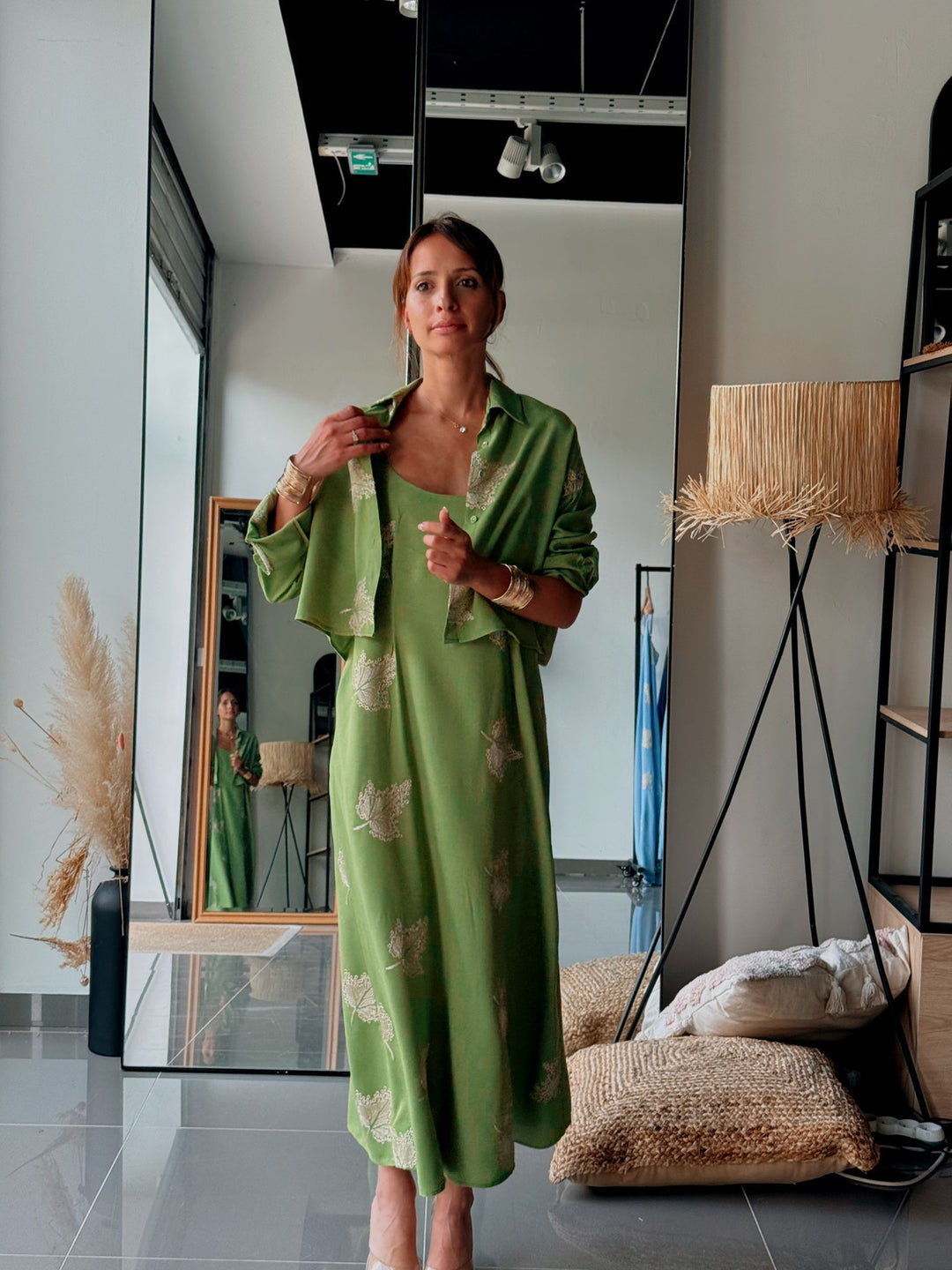 Woman in a green dress standing in a modern interior setting.